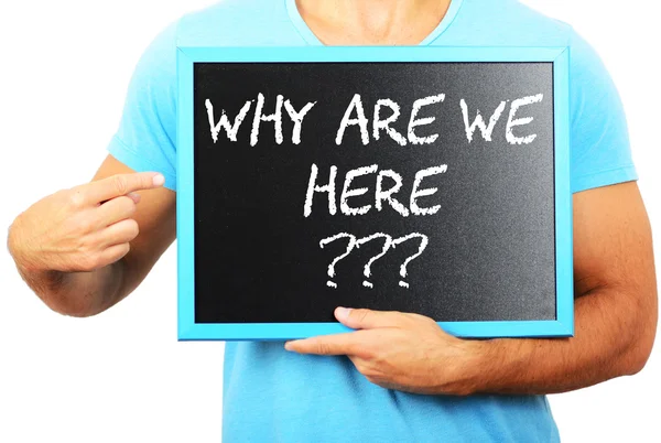 Man holding blackboard in hands and pointing the word WHY ARE WE — Stock Photo, Image