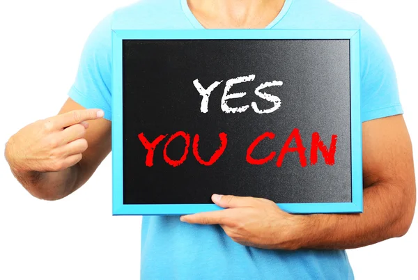Чоловік тримає дошку в руках і вказує слово "YES you CA" — стокове фото