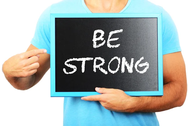 Man holding blackboard in hands and pointing the word BE STRONG — Stock Photo, Image