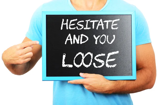 Man holding blackboard in hands and pointing the word HESITATE A — Stock Photo, Image