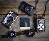 Vinobraní fotoaparát s objektivy a prázdné staré fotografie na dřevěných ba