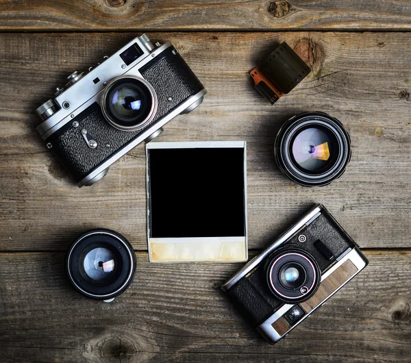 Vintage cameras with lenses and blank old photograph on wooden b — Stock Photo, Image