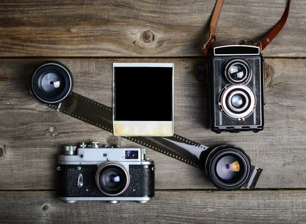 Vintage cameras with lenses and blank old photograph on wooden b — Stock Photo, Image