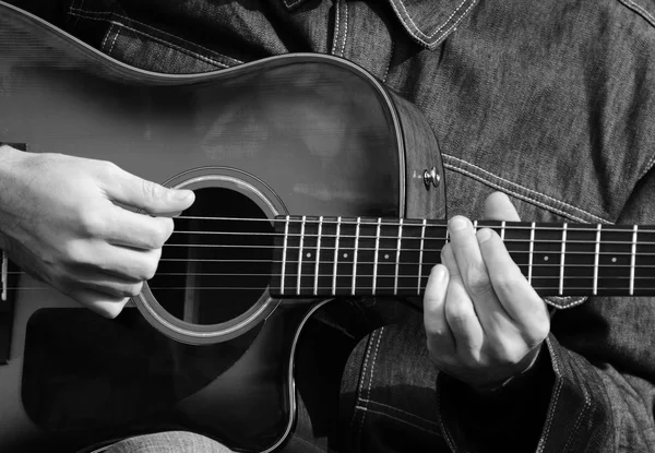 Close up de mãos masculinas tocando guitarra em preto e branco — Fotografia de Stock