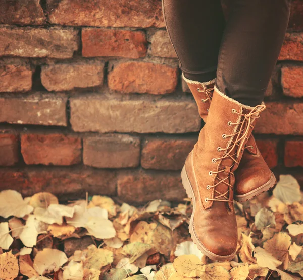 Conceptuele afbeelding van benen in de boots op de herfst bladeren - wandelen — Stockfoto