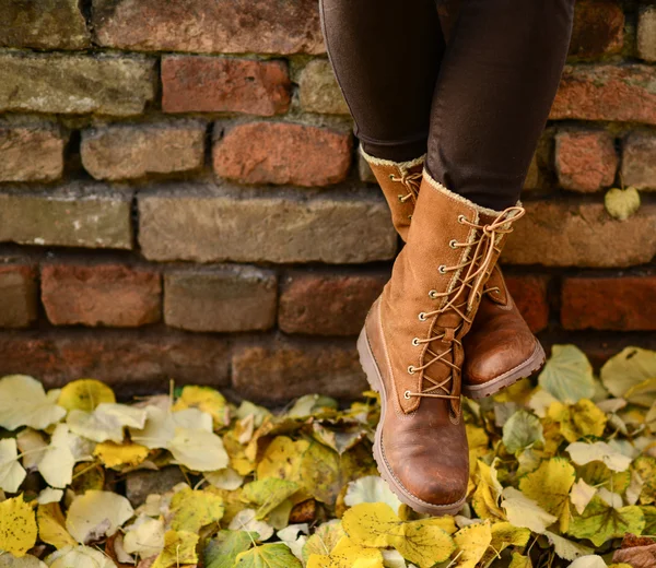 Conceptuele afbeelding van benen in de boots op de herfst bladeren - wandelen — Stockfoto