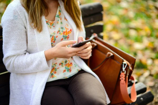 Kvinna med mobiltelefon i parken — Stockfoto