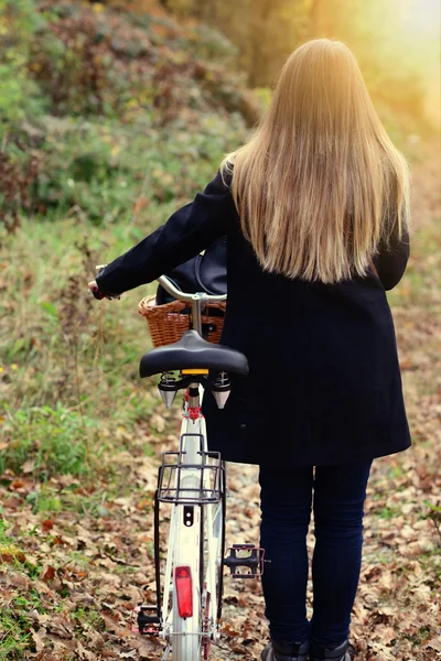 Flicka Rider en cykel i skogen vid solnedgången — Stockfoto