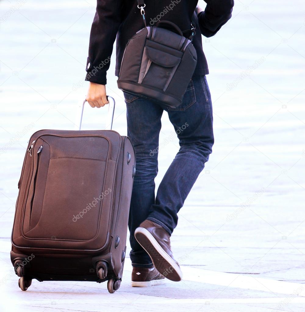 Traveler man walking with suitcase in the street