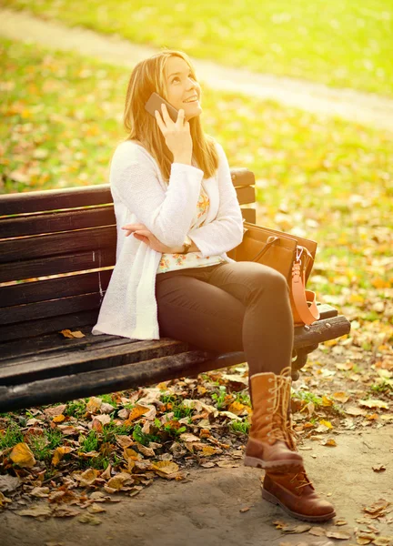 Happy young woman talking on phone in Autumn park — Stock Photo, Image