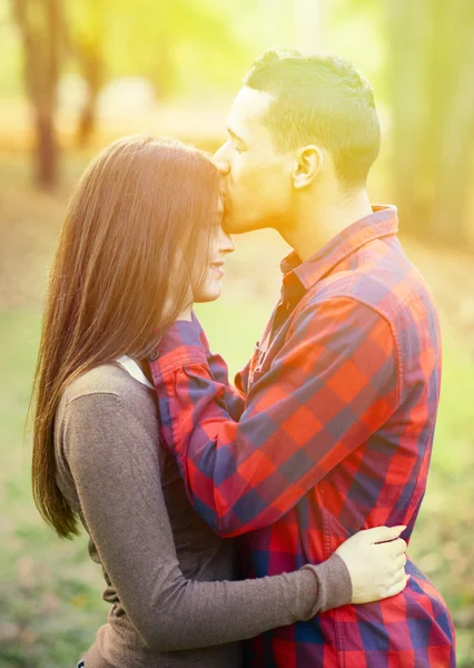 Close up of boy kissing girlfriend on forehead outdoor — Stock Photo, Image