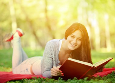 park içinde gülümseyen güzel kadın okuma kitabı