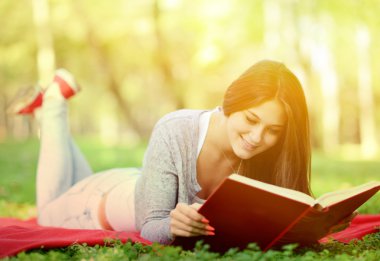 park içinde gülümseyen güzel kadın okuma kitabı