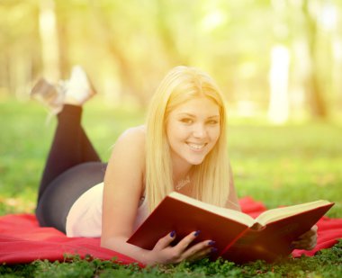 park içinde gülümseyen güzel kadın okuma kitabı