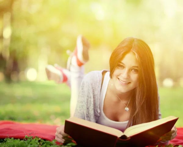 Bella donna sorridente leggere libro nel parco — Foto Stock