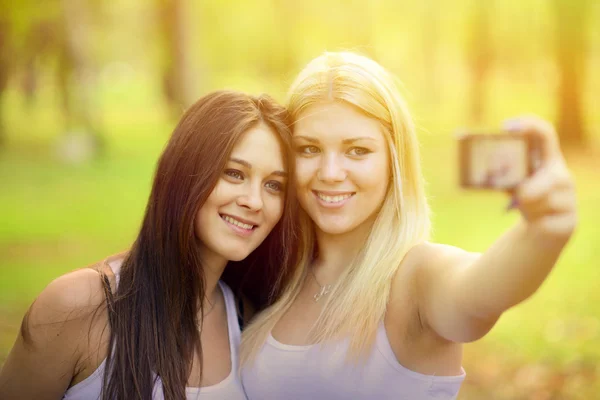 Retrato ao ar livre de duas amigas tirando fotos com câmera — Fotografia de Stock