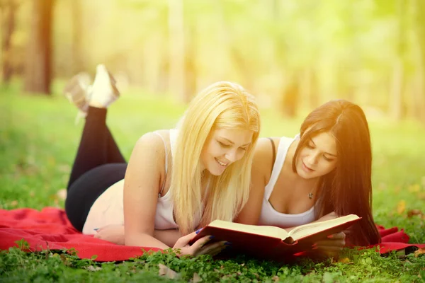 Två tjejer läser bok i parken — Stockfoto