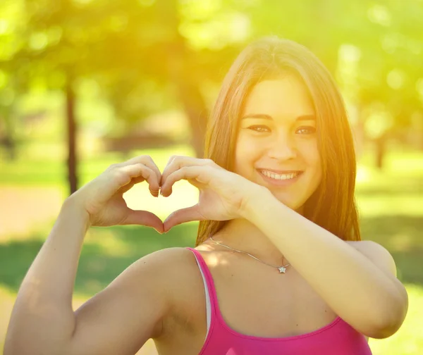 Leuke tiener meisje waardoor hart vorm met haar handen buitenshuis — Stockfoto