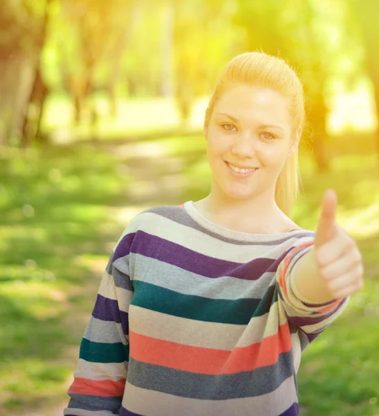 Portrait of beautiful girl holding thumbs up outdoors — Stock Photo, Image