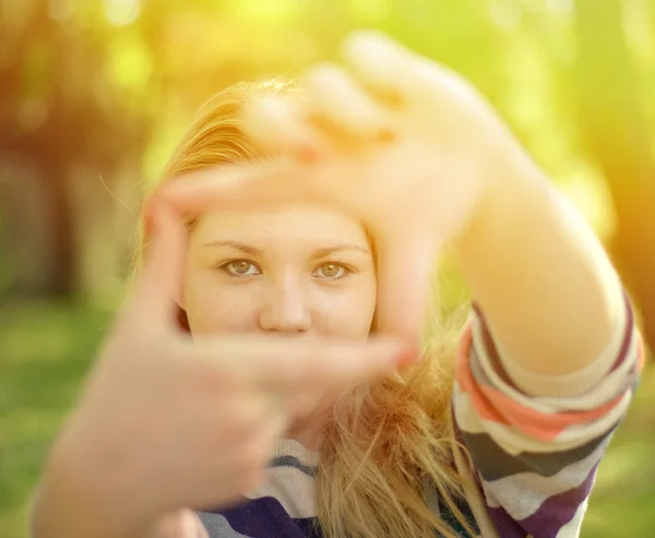 Beautiful girl making frame with hands while outdoors — Stock Photo, Image