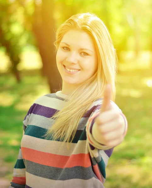 Beautiful teenage girl holding thumbs up outdoors — Stock Photo, Image