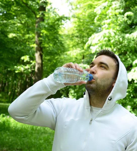 Adatto giovane sportivo che beve acqua dalla bottiglia di plastica dopo wor — Foto Stock