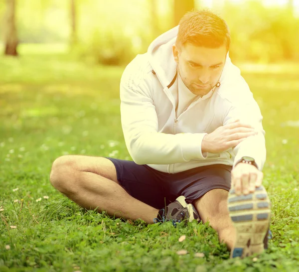 Handsome sportsman stretching outdoors — Stock Photo, Image
