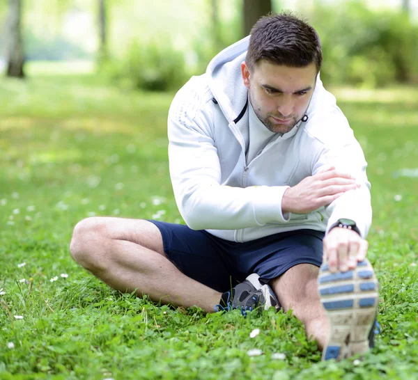 Guapo deportista estirándose al aire libre — Foto de Stock