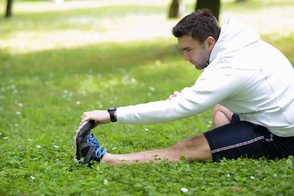 Handsome sportsman stretching outdoors — Stock Photo, Image