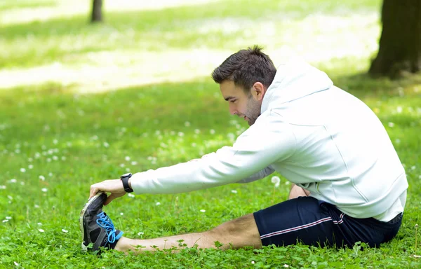 Schöner Sportler dehnt sich im Freien — Stockfoto