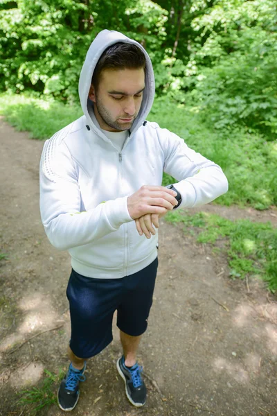 Runner sul sentiero di montagna guardando orologio intelligente sport — Foto Stock