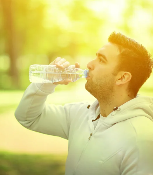 Adatto giovane sportivo che beve acqua dalla bottiglia di plastica dopo wor — Foto Stock