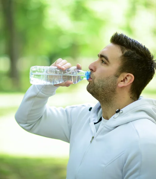 Adatto giovane sportivo che beve acqua dalla bottiglia di plastica dopo wor — Foto Stock