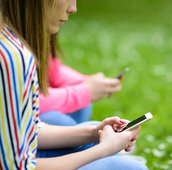 Närbild av tonårsflickor händer att använda mobiltelefoner utomhus — Stockfoto