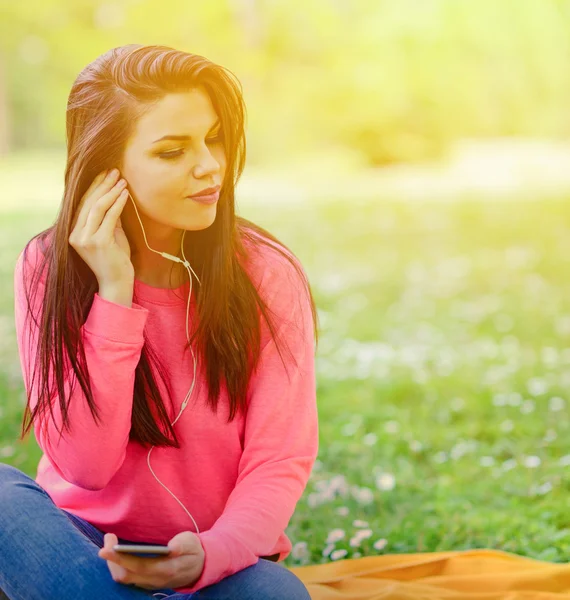 Mujer estudiante fuera en parque escuchando música en headph —  Fotos de Stock