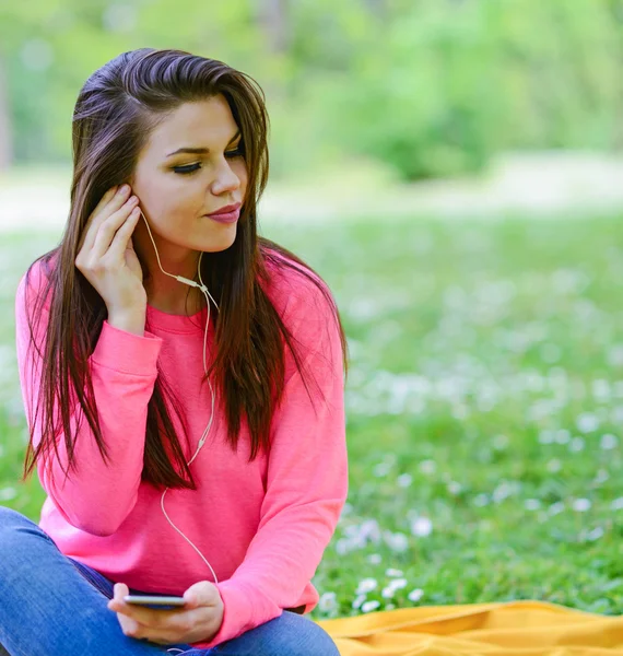 Kvinnlig student tjej utanför i park lyssna på musik på headph — Stockfoto