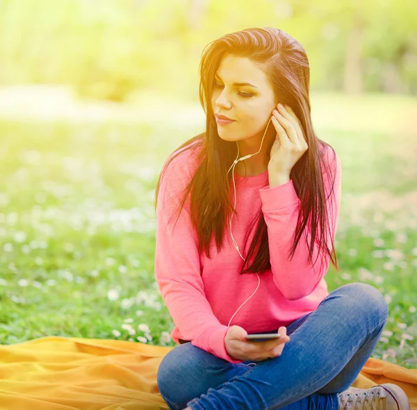 Kvinnlig student tjej utanför i park lyssna på musik på headph — Stockfoto