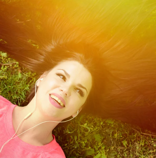 Meisje luisteren naar muziek, terwijl liggend op gras tijdens zomerdag — Stockfoto