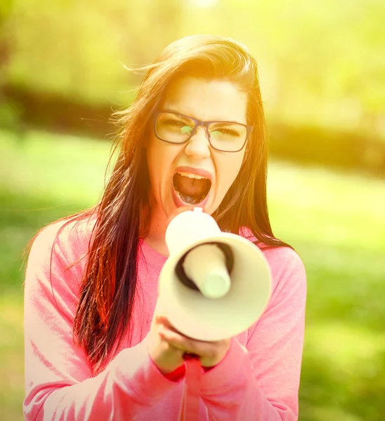 Portrait of middle aged woman shouting using megaphone against a — Stock Photo, Image