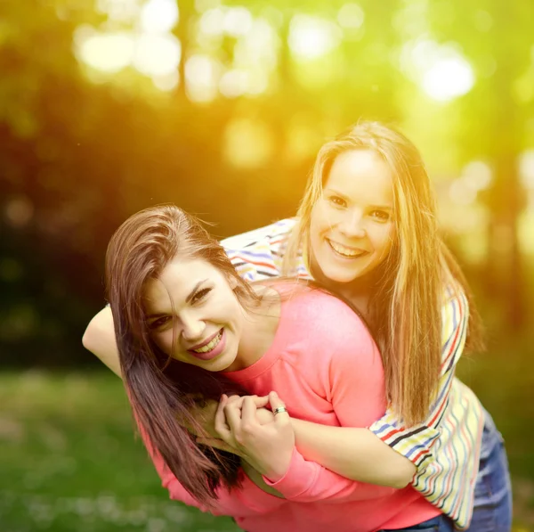 Två unga flicka vänner i en kram på park — Stockfoto