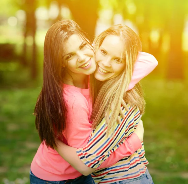 Two young girl friends in a hug at park — Stock Photo, Image