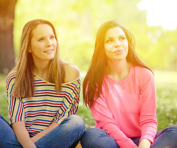 Two young girl friends sitting on grass at summer day — Stock Photo, Image