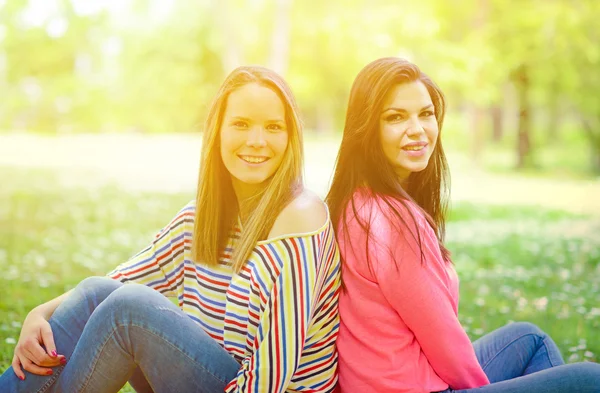 Two young girl friends sitting on grass at summer day — Stock Photo, Image