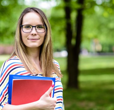 Elleri kitapta kadınla genç mutlu öğrenci duruyor