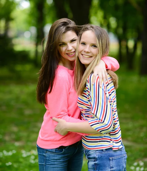 Two young girl friends together in hug at park — Stock Photo, Image