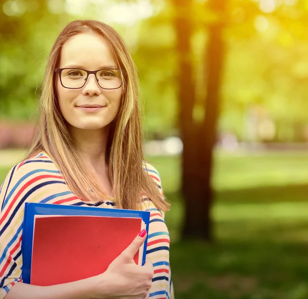 Elleri kitapta kadınla genç mutlu öğrenci duruyor