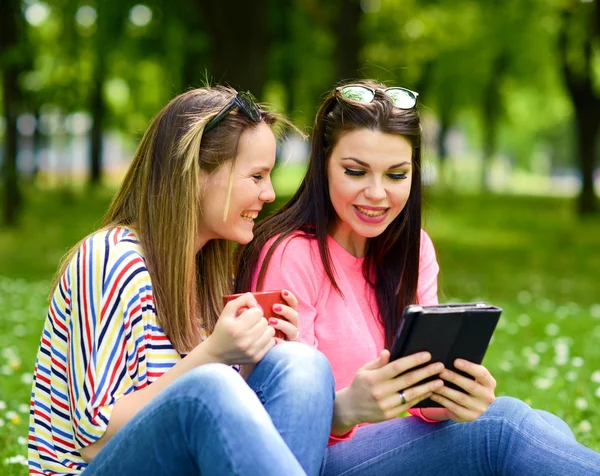 Young women drinking coffee and browsing internet on tablet at p — Stock Photo, Image