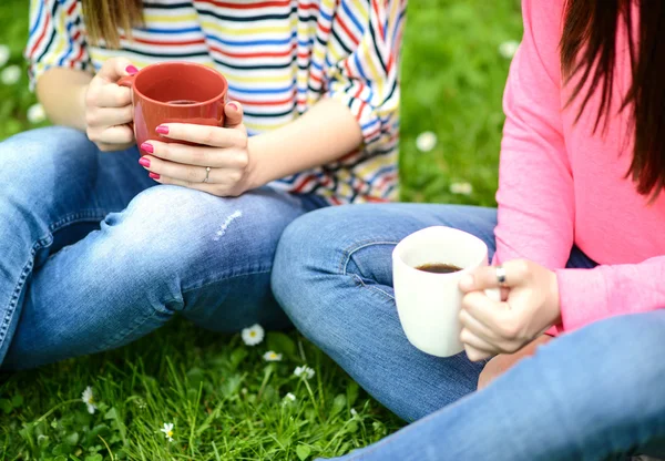 Young women drinking coffee at park and enjoying summer day