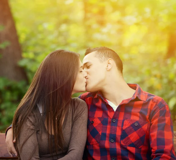 Couple kissing at the bench in park — Stock Photo, Image