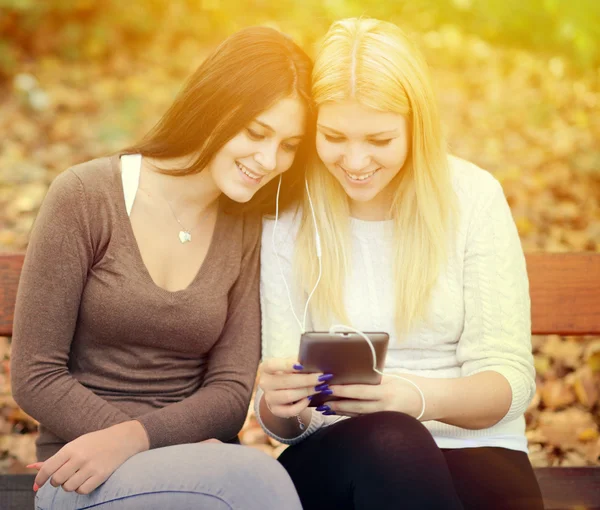 Två unga kvinnor tittar på tavlan och chating online med vän — Stockfoto